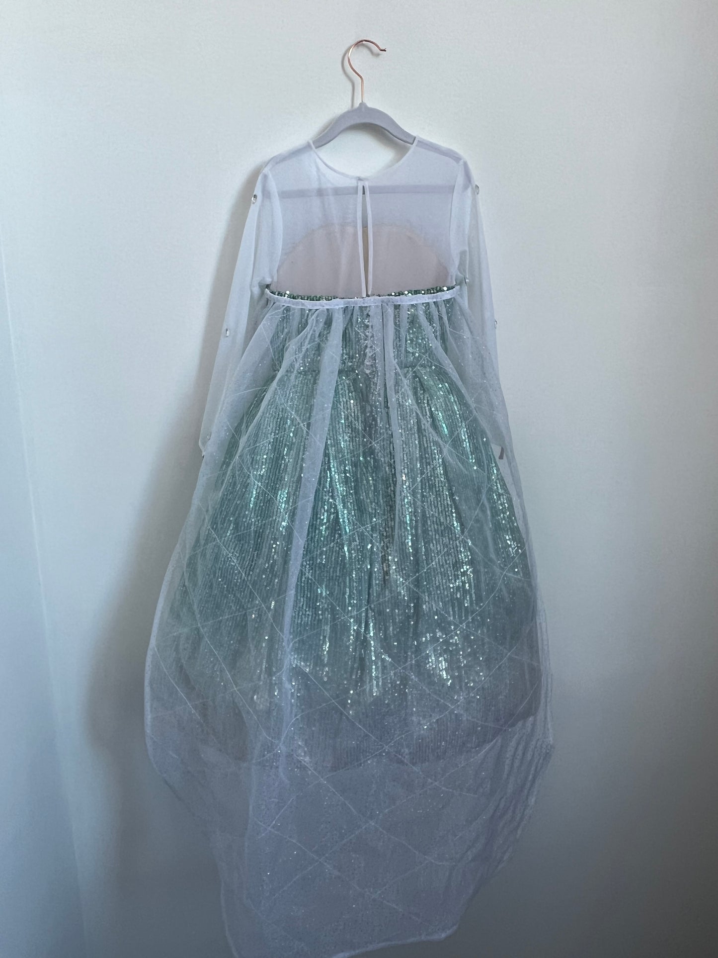 Elsa Dress-Up Costume featuring soft sequins with a frosty ombré finish, a full petticoat for twirling, and stretchy power mesh sleeves. Fastened with captivating crystal buttons and includes a detachable floor-length cape for dramatic flair. Personalized hand-embroidery option available inside the silky soft lining.