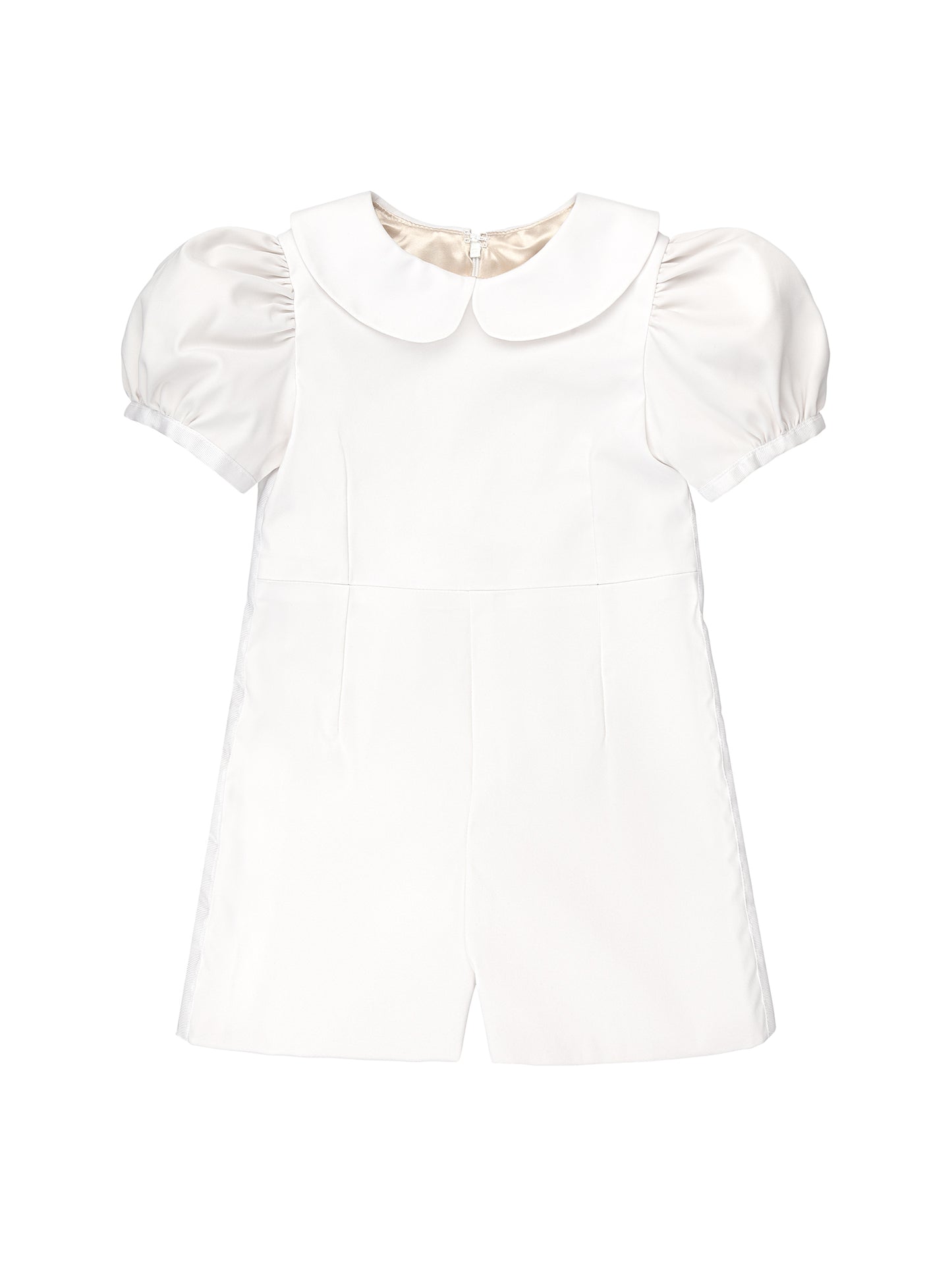 The Melissa romper blends traditional flower girl elegance with playful tap pants. Features puff sleeves, a Peter Pan collar, grosgrain ribbon trim, and easy-to-move shorts. Back pearl button closure with a zipper on the shorts and a hand-tied sash for a polished finish. Handcrafted in Brooklyn from cotton and satin, with optional personalized embroidery. Detachable skirt and custom colors available upon request.