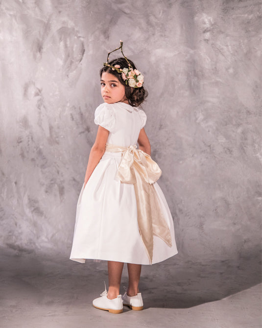 The Rachel – classic flower girl dress with precise seams, puffed sleeves, and a box-pleated skirt. Features a timeless Peter Pan collar, back zip closure, and adjustable petticoat volume. Crafted from satin, silk, and tulle with a silky soft lining, perfect for elegant weddings and special occasions.