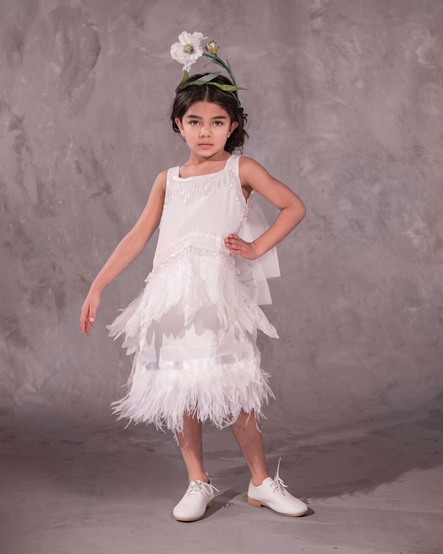 The Imogen, an art deco-inspired A-line dress featuring beaded fringe, silk, velvet, and a playful layer of ostrich feathers. Designed for movement and elegance, complete with an oversized satin bow. Fully lined with a silky soft finish and a side zip closure. Handcrafted in Brooklyn with optional personalized embroidery. Perfect for weddings, parties, and special occasions.