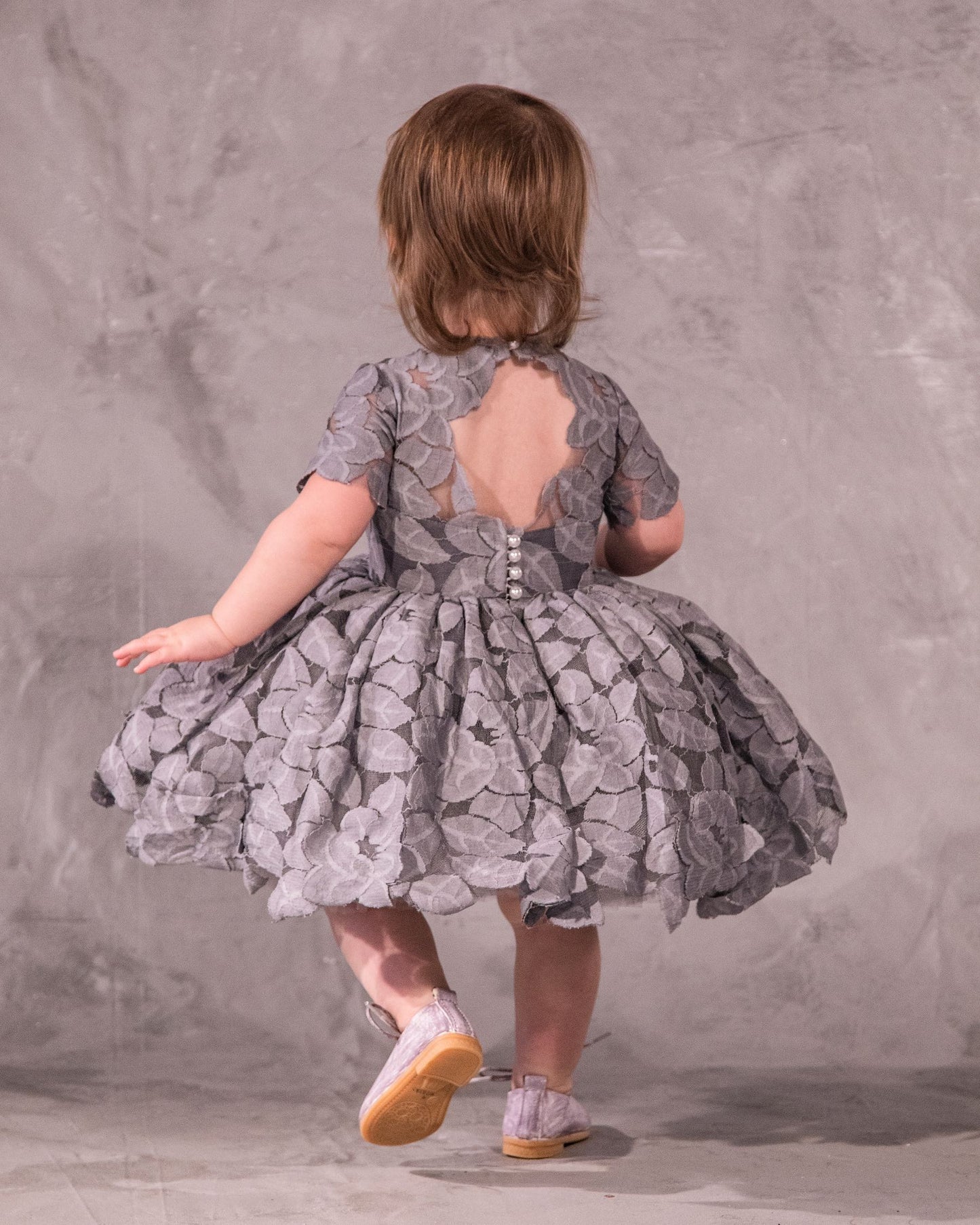 The Baby Annabelle – handcrafted cotton floral lace baby dress with a keyhole back and pearly button closure. Features a full twirl-worthy skirt, silky soft lining, and personalized embroidery. Perfect for first special occasions, weddings, communions, and celebrations