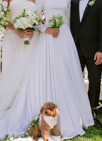 Two people in wedding attire with a dog with a bespoke wedding outfit