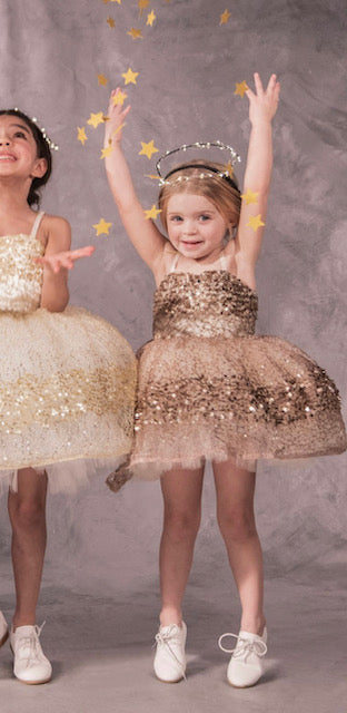 A sparkly, rose gold colored dress with glittery paillettes and woven metallic threads, featuring a plush petticoat and adjustable grosgrain ribbon straps for birthday celebrations and black tie weddings