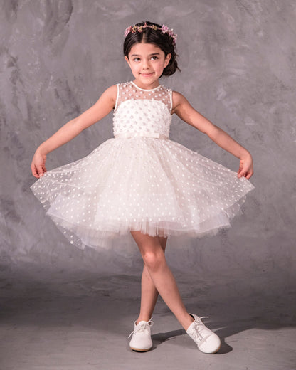 The Pearl flower girl dress featuring intricate pearl embellishments on an illusion neckline and bodice. Swiss dot tulle skirt with a twirly high-low hem, finished with a satin bow. 