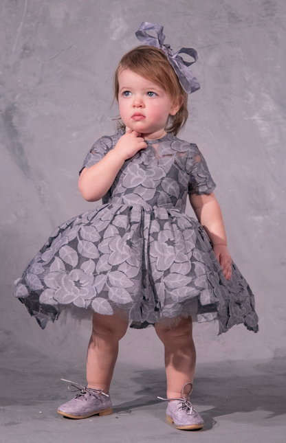 The Baby Annabelle – handcrafted cotton floral lace baby dress with a keyhole back and pearly button closure. Features a full twirl-worthy skirt, silky soft lining, and personalized embroidery. Perfect for first special occasions, weddings, communions, and celebrations
