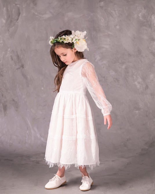 A white, vintage-style dress with sheer sleeves and lace detailing, designed for children, for bohemian and spring-summer weddings