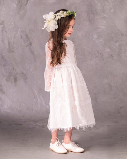 A white, vintage-style dress with sheer sleeves and lace detailing, designed for children, for bohemian and spring-summer weddings